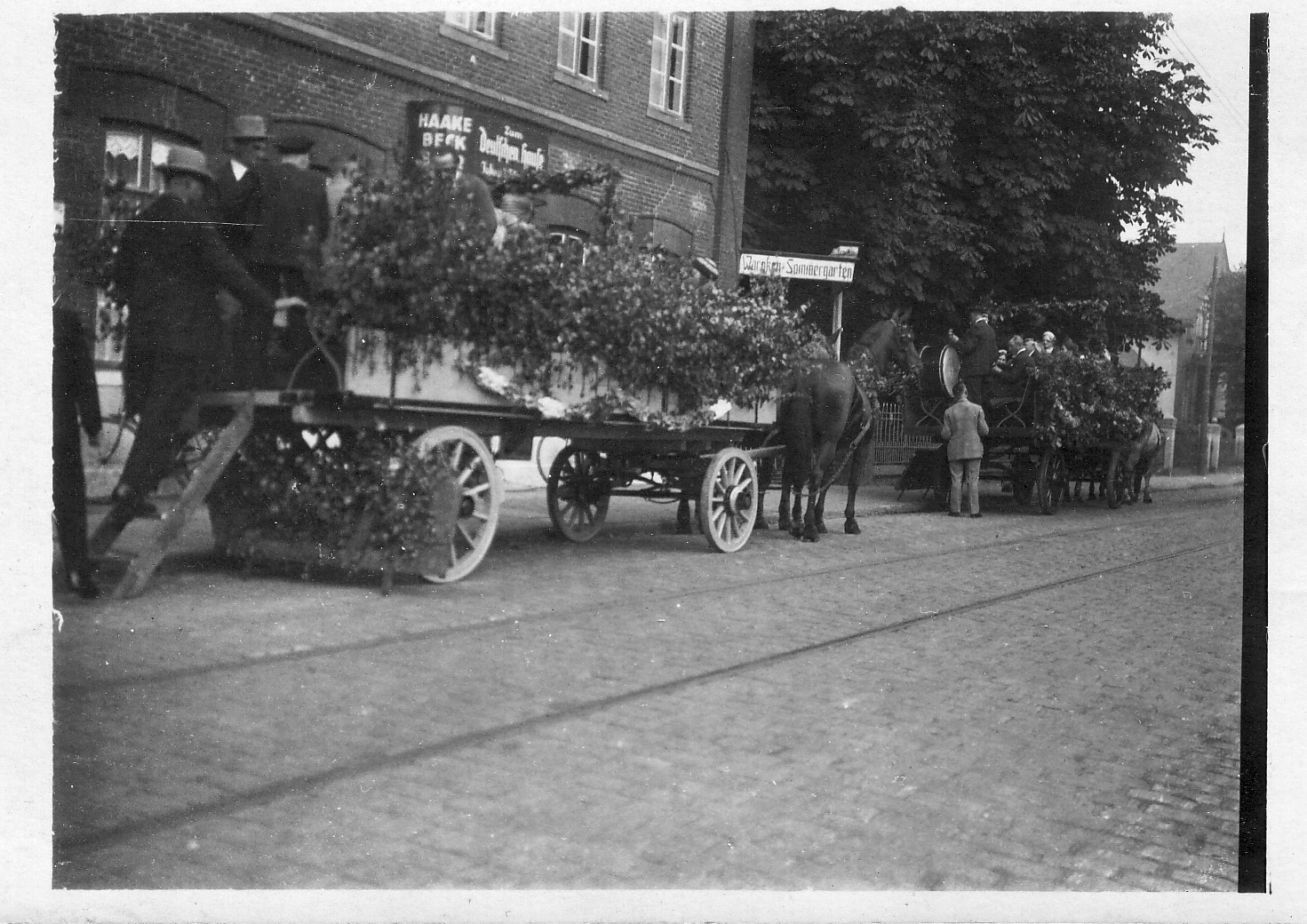 Vorbereitungen zum Erntedankfest vor dem Deutschen Haus /Auf dem rechten, ersten Wagen sitzt schon die Blaskapelle 